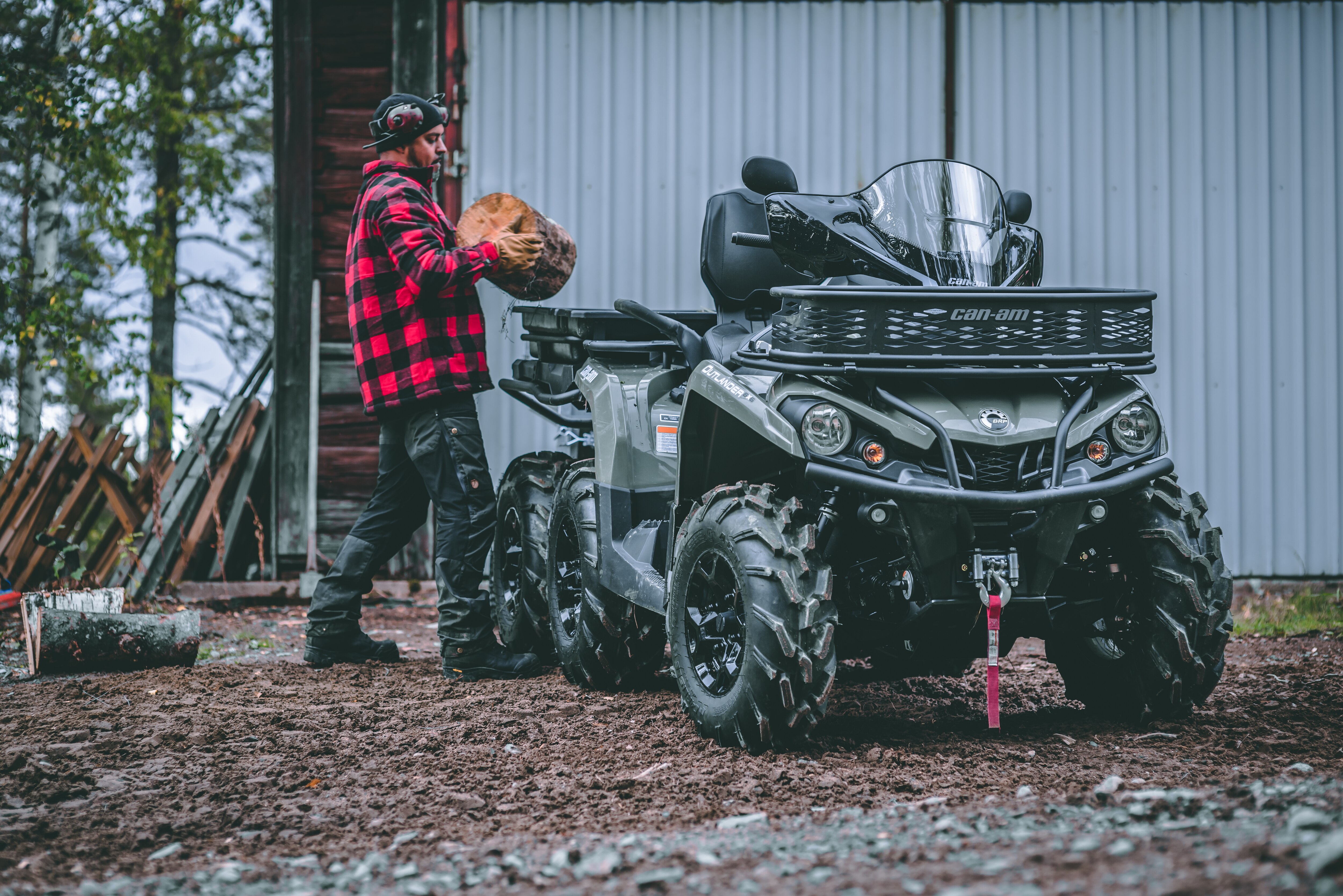 Un homme met du bois dans le rangement arrière de son VTT Can-Am Outlander 6x6 PRO