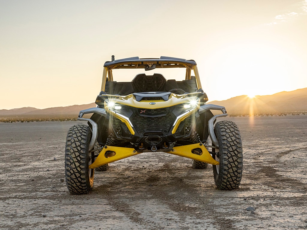 Un Can-Am Maverick R SxS aparcado con las luces encendidas en el desierto