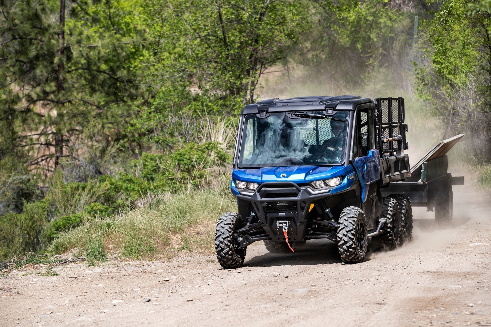 Un Can-Am Defender 6x6 color Oxford Blue en accion, arrastrando un remolque.