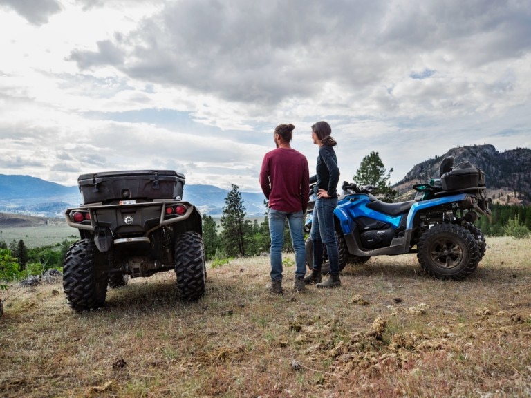 A couple next to their ATVs admiring the mountains view